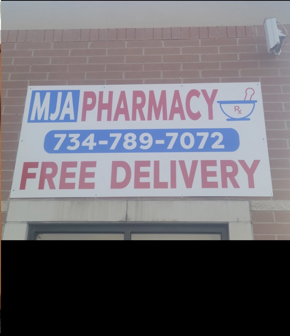 MJA Pharmacy storefront sign showing free delivery